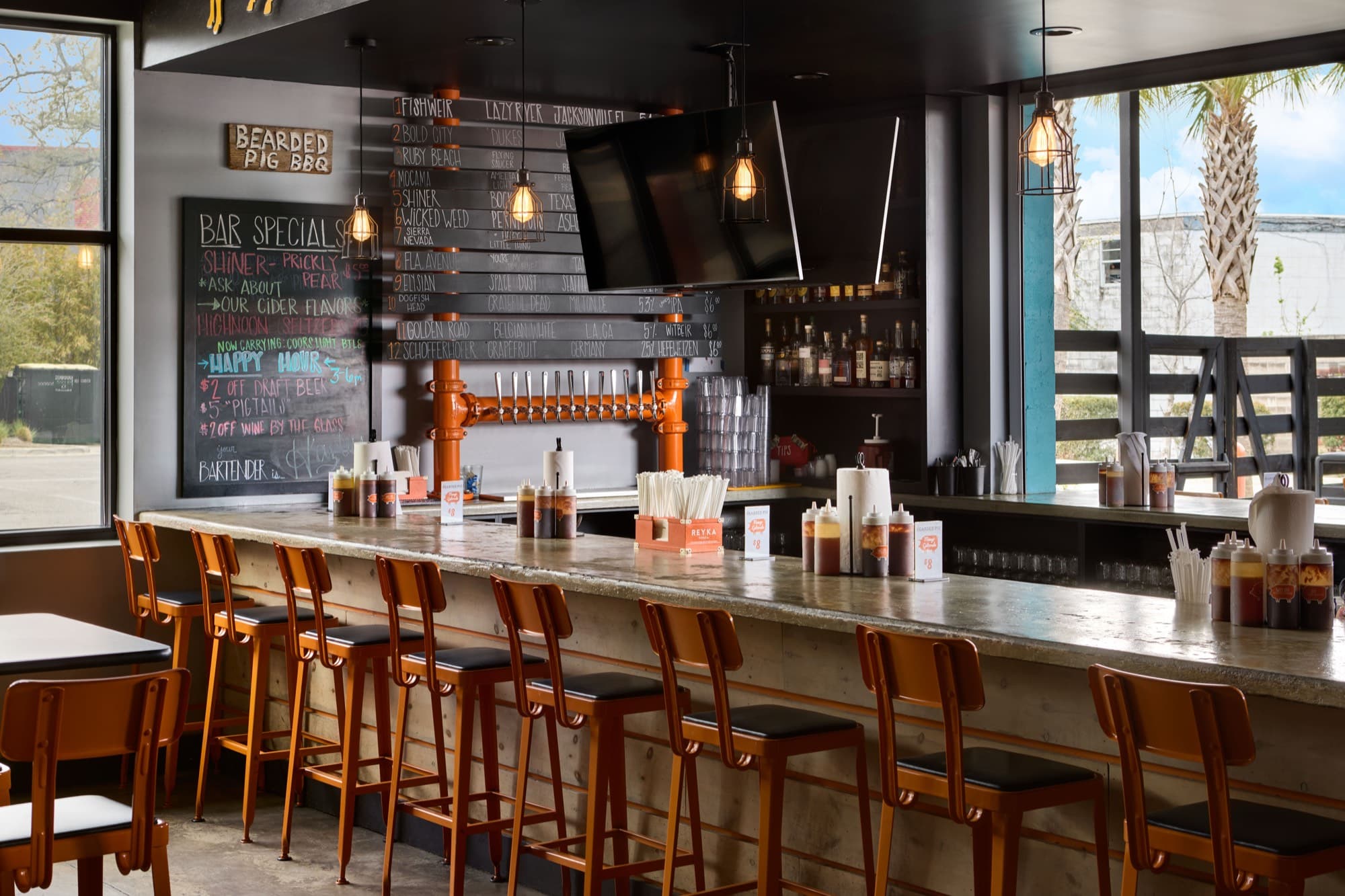 Craft beer taps and orange bar stools at The Bearded Pig's full bar