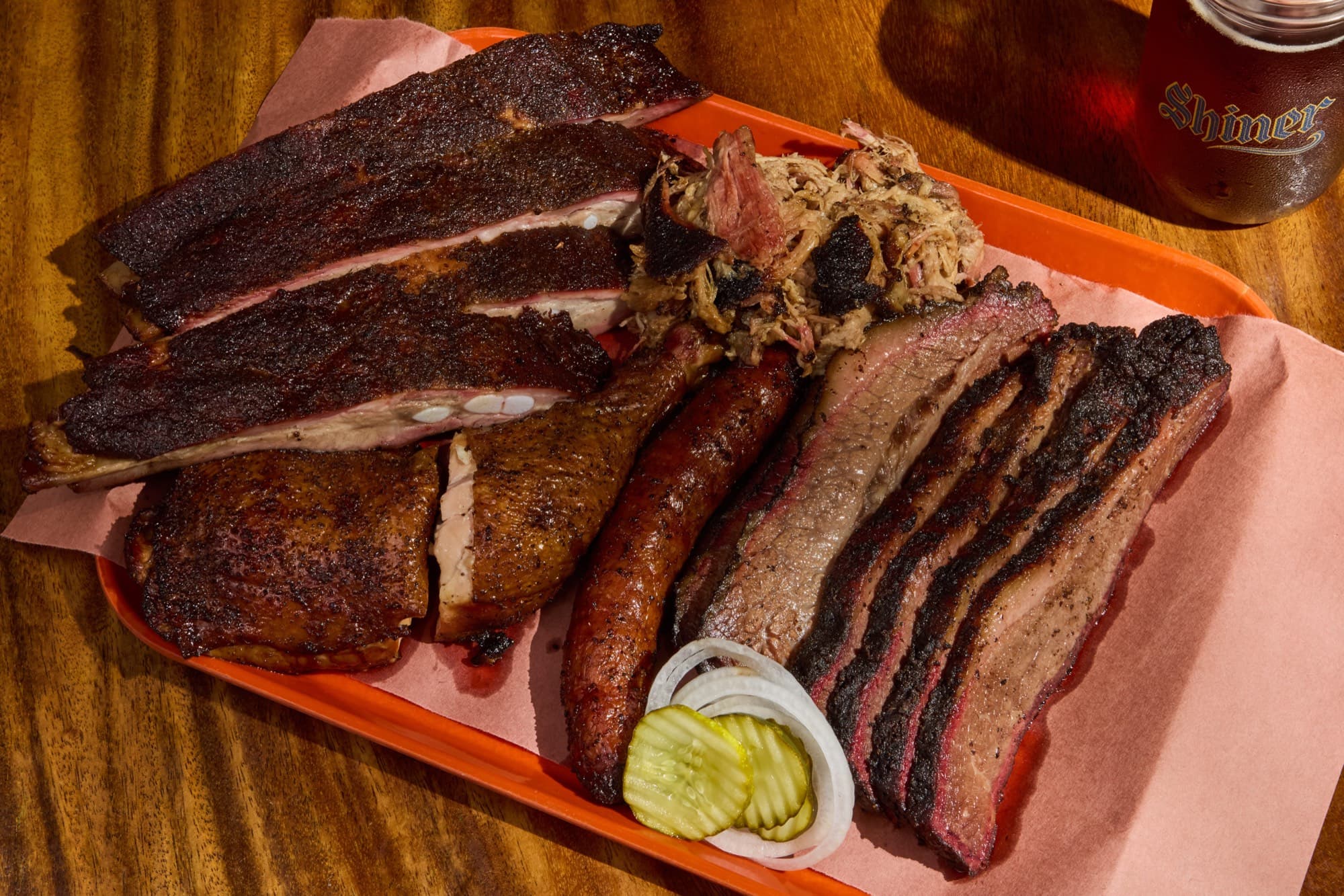 An overhead barbecue sampler tray with brisket, ribs and sausage